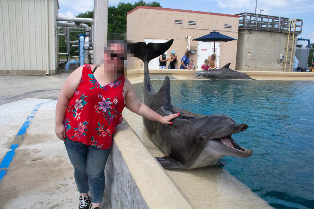 Turist i nærkontakt med vild delfin i delfinarium